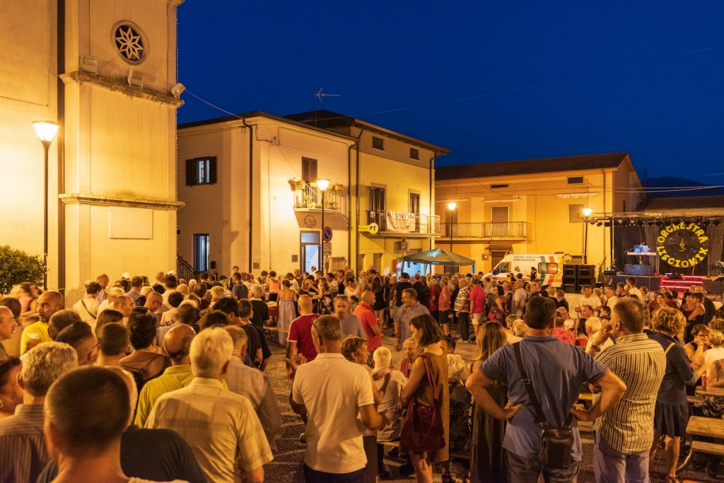 Crowd gathered for an outdoor evening festival event with stage.